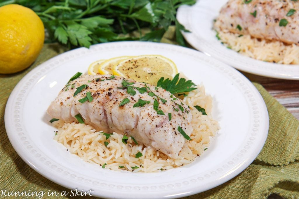Baked Grouper on a plate with lemons and rice.