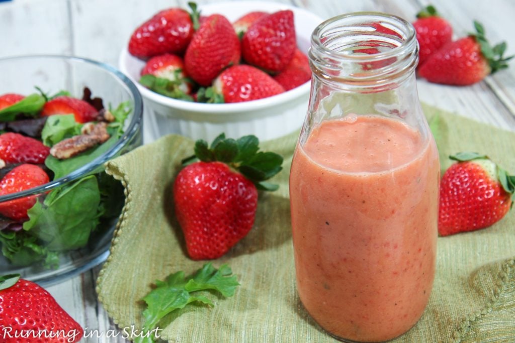 Strawberry Vinaigrette Dressing in a jar with salad on the side.